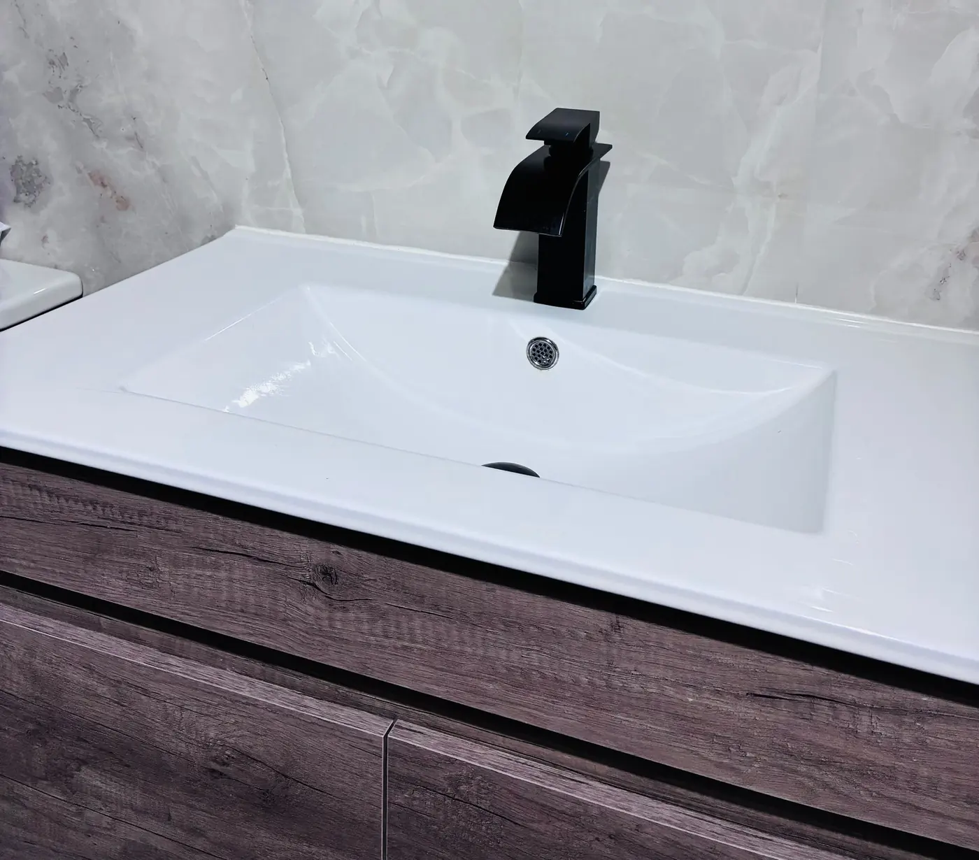 Detalle del lavabo y el grifo negro mate en un baño recién instalado.